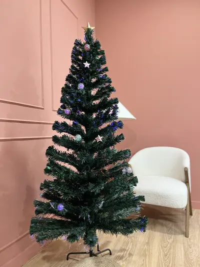 Árbol de fibra óptica con estrellas junto a un sillón